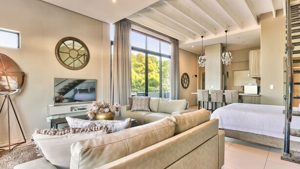 A modern living room with a large sofa, a television, and a dining area with chairs. - Heritage Square Apartments (Cape Town)