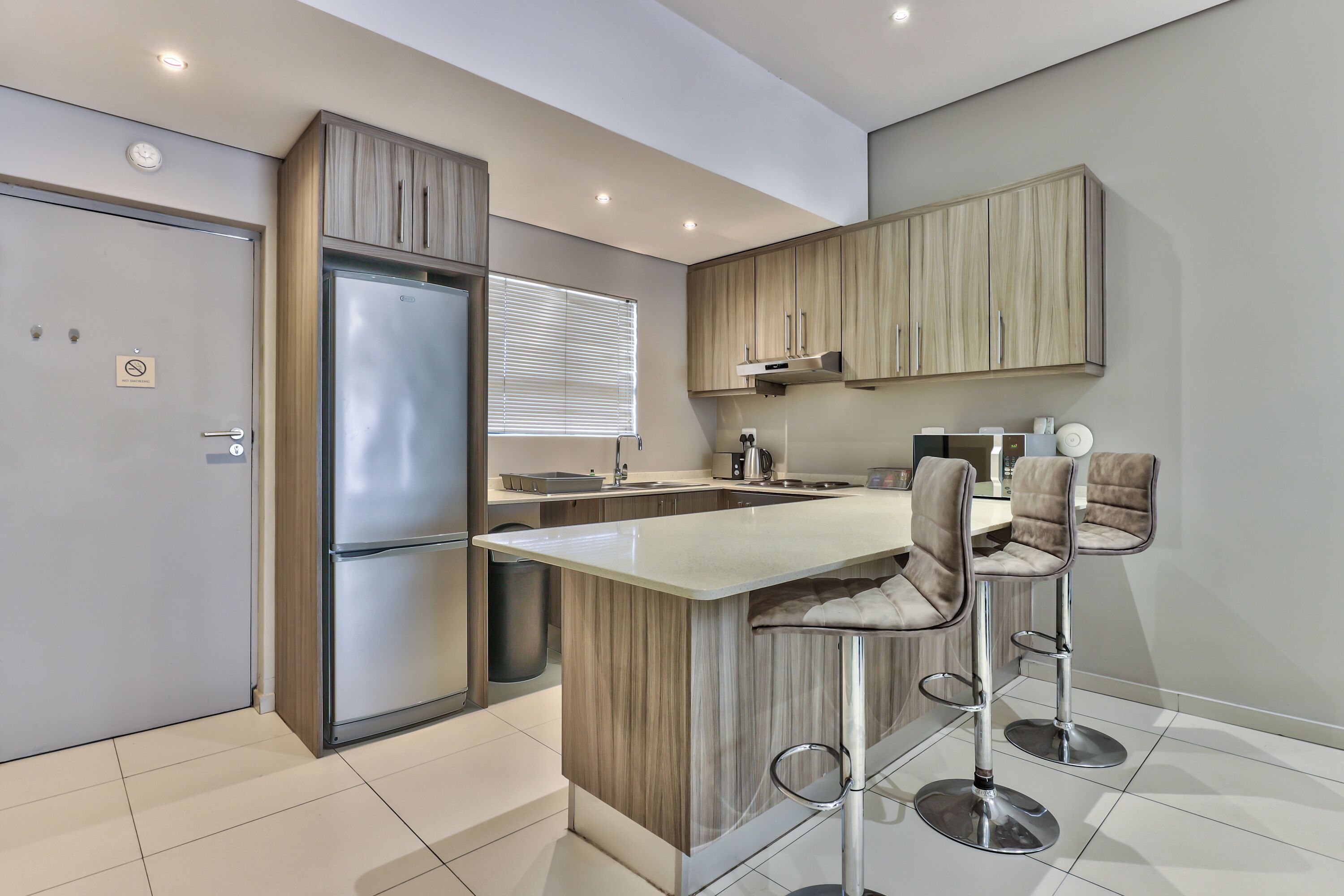 A modern kitchen with a built-in island, stainless steel appliances, and bar stools.