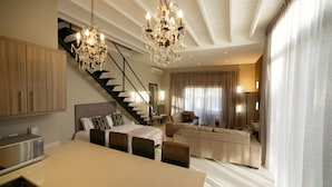 A spacious living area with a dining table, sofa, and a staircase leading to another level. - Heritage Square Apartments (Cape Town)