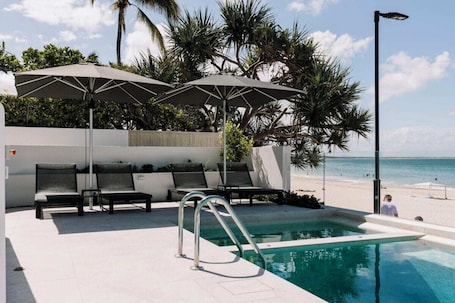 Una piscina al aire libre, sillones reclinables de piscina