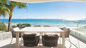 A balcony with a white table and wicker chairs, overlooking a beach and ocean. - La Mer Noosa (Noosa Heads)
