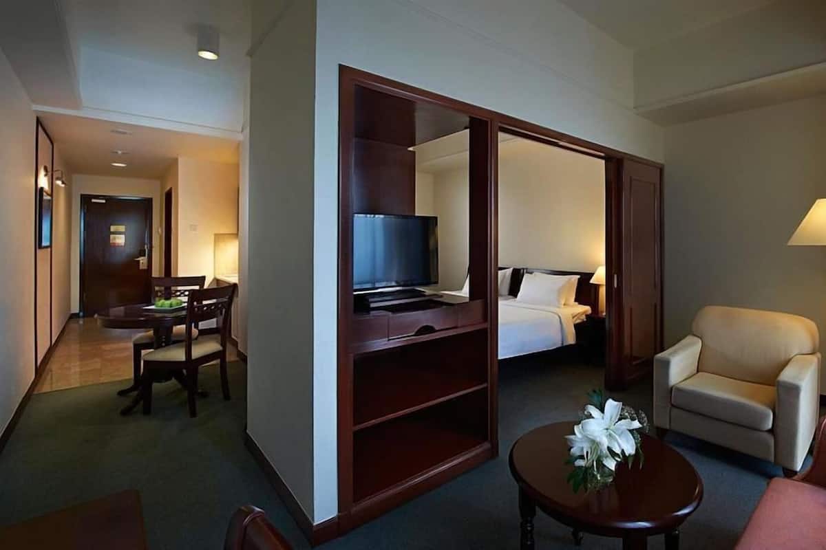 A hotel room with a bed, a TV, a desk, a chair, and a lamp.