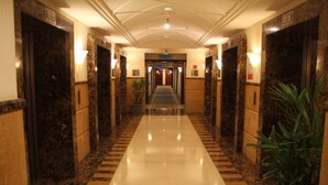 A hotel corridor with marble walls, a checkered floor, and a central hallway leading to a door marked "Lobby".