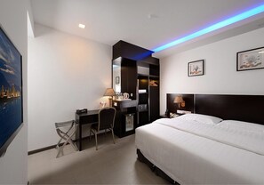 A hotel room with a bed, desk, chair, and a large window with a cityscape view. - ERNES Hotel Bandar Perda (Bukit Mertajam)