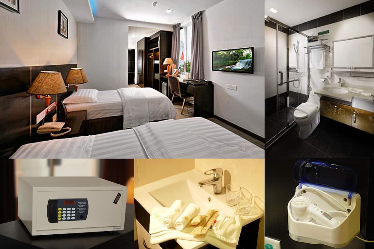 A hotel room with two beds, a TV, a desk, and a bathroom with a shower, toilet, and sink.