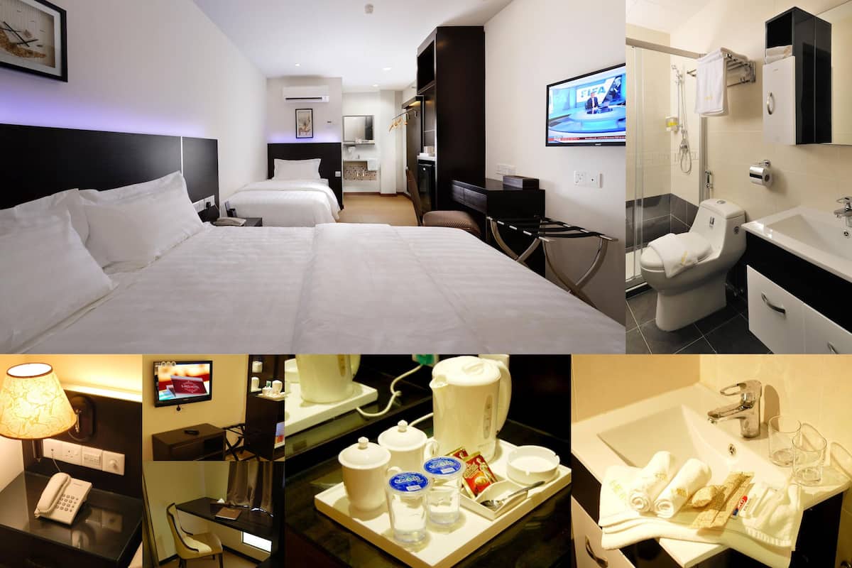 A hotel room with a large bed, a desk with a computer, a TV, and a bathroom with a sink and toilet.