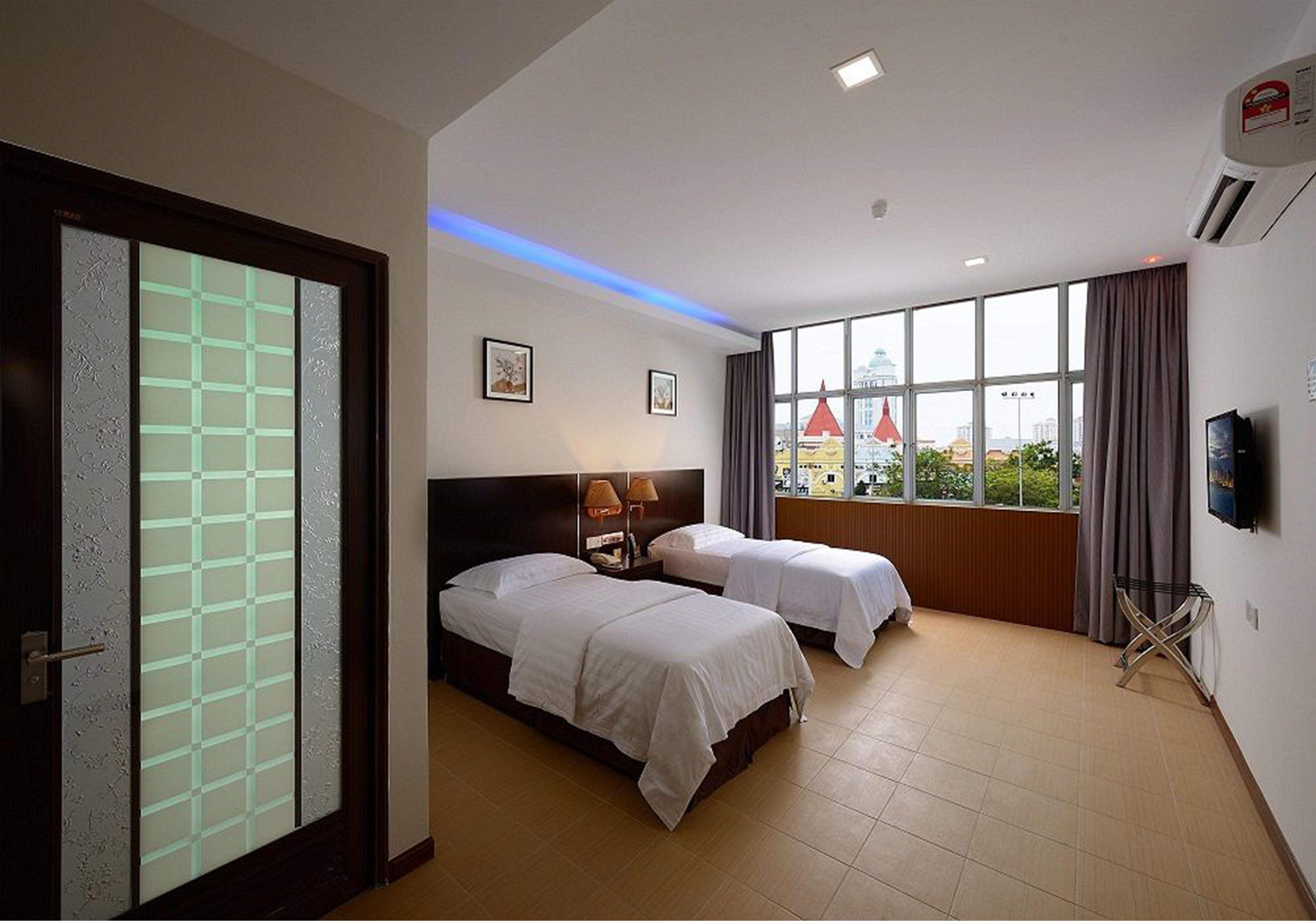 Een hotelkamer met twee bedden, een groot raam met uitzicht en een aan de muur bevestigde televisie.