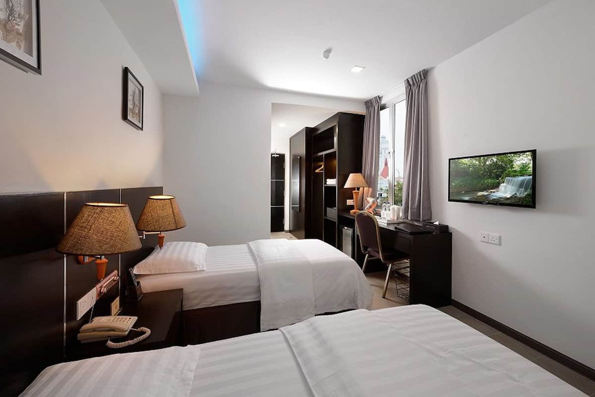 A hotel room with two beds, a desk, a television, and a bathroom visible through an open door.