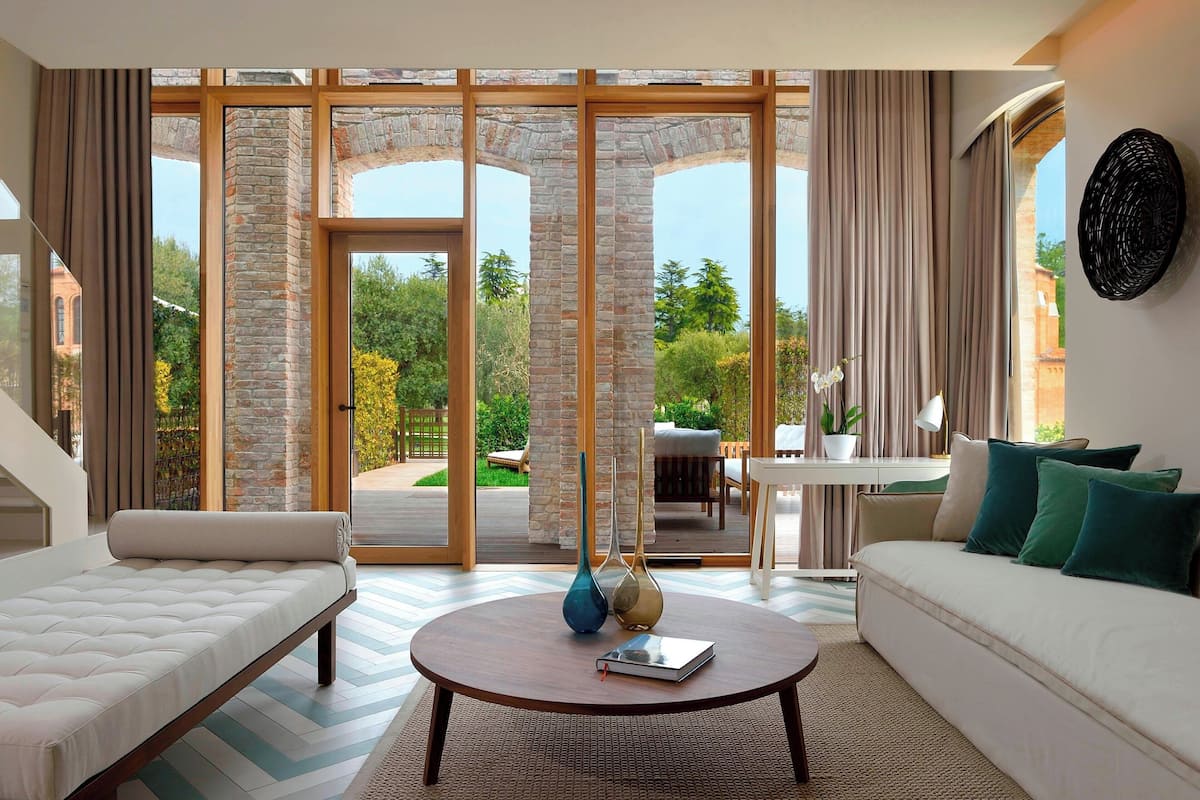 A modern living room with a sofa, a coffee table, and a view through large glass doors to an outdoor patio.