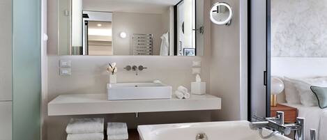 Une salle de bain moderne avec un grand miroir, un lavabo blanc et une baignoire.