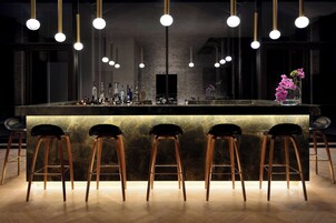 Un'area bar con un bancone in marmo, tre sgabelli e lampade a sospensione.