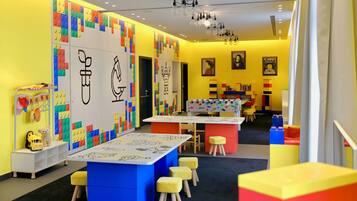 Un área de juegos infantil de colores brillantes, con paredes, mesas y taburetes de LEGO.