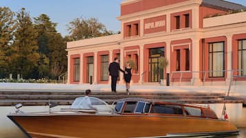 A wooden boat docked at a building with a red facade and the name "DOPOLAVORO" visible.