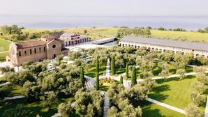 An aerial view of a campus with a large building, a smaller structure, and a long corridor with trees. - JW Marriott Venice Resort & Spa (Venice)