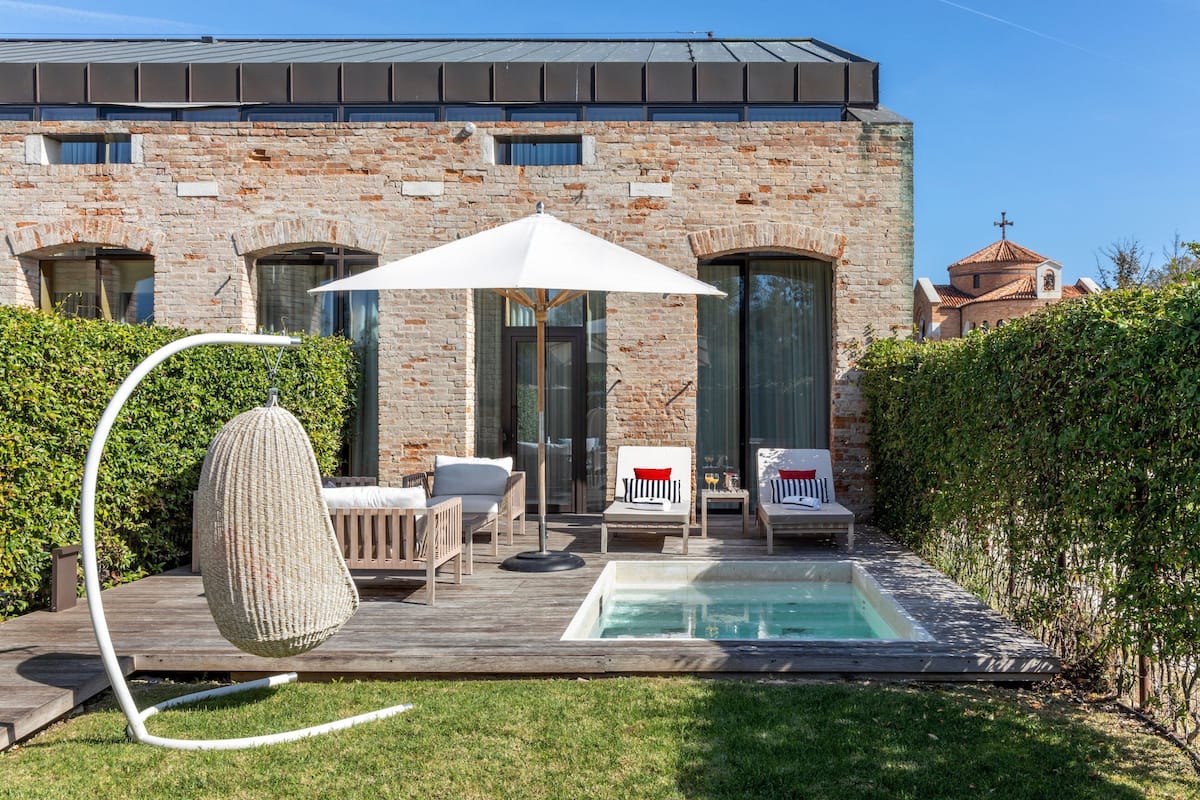 A modern house with a brick exterior, a swimming pool, and outdoor seating.
