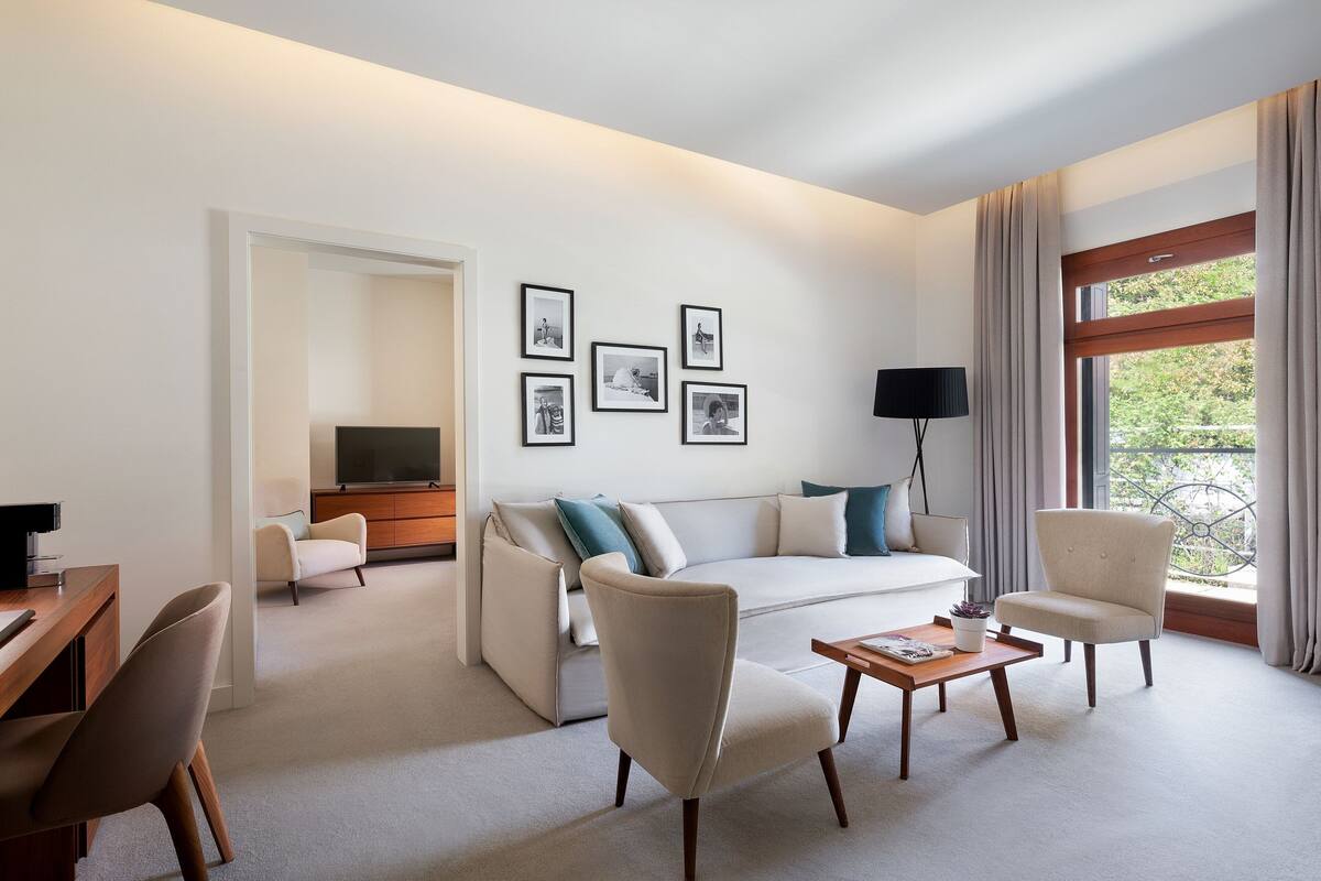 A modern living room with a sofa, armchairs, a coffee table, and a TV.