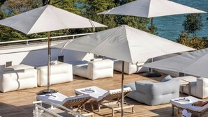 A rooftop terrace with white umbrellas, lounge chairs, and a view of a cityscape across a body of water. - JW Marriott Venice Resort & Spa (Venice)