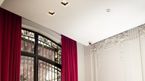 A room with a checkered floor, a white console table, a desk with a lamp, and a window with red curtains. - Tango de Mayo Hotel (Buenos Aires)