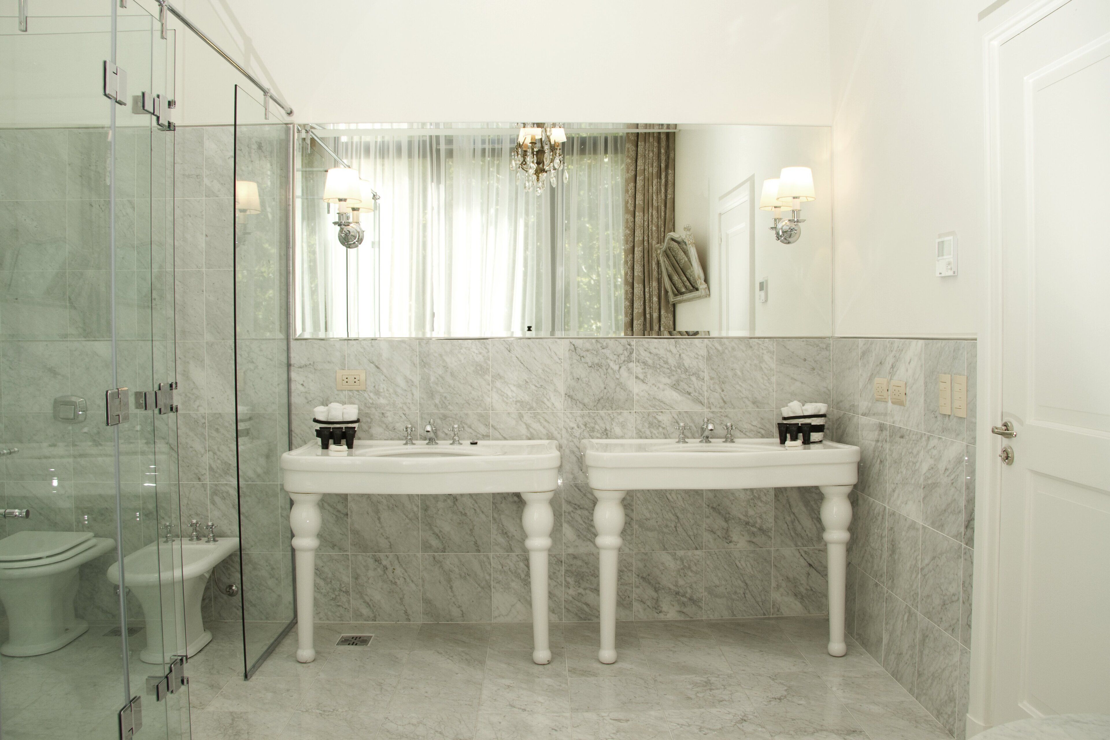 Une salle de bain avec deux lavabos, une douche à parois de verre et un grand miroir.