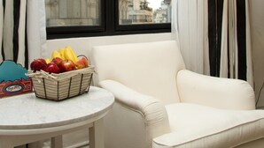 A room with a view of a historic building, a white armchair, a small table with a fruit basket, and a floor lamp. - Tango de Mayo Hotel (Buenos Aires)