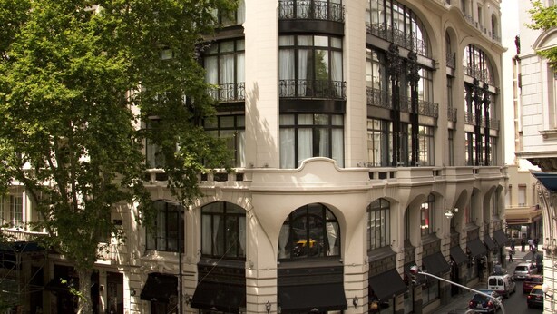 A multi-story building with large windows and balconies, a crosswalk, and a street with cars and pedestrians. - Tango de Mayo Hotel (Buenos Aires)
