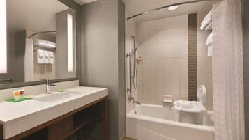 A modern bathroom with a double sink vanity, a bathtub, and a shower area.