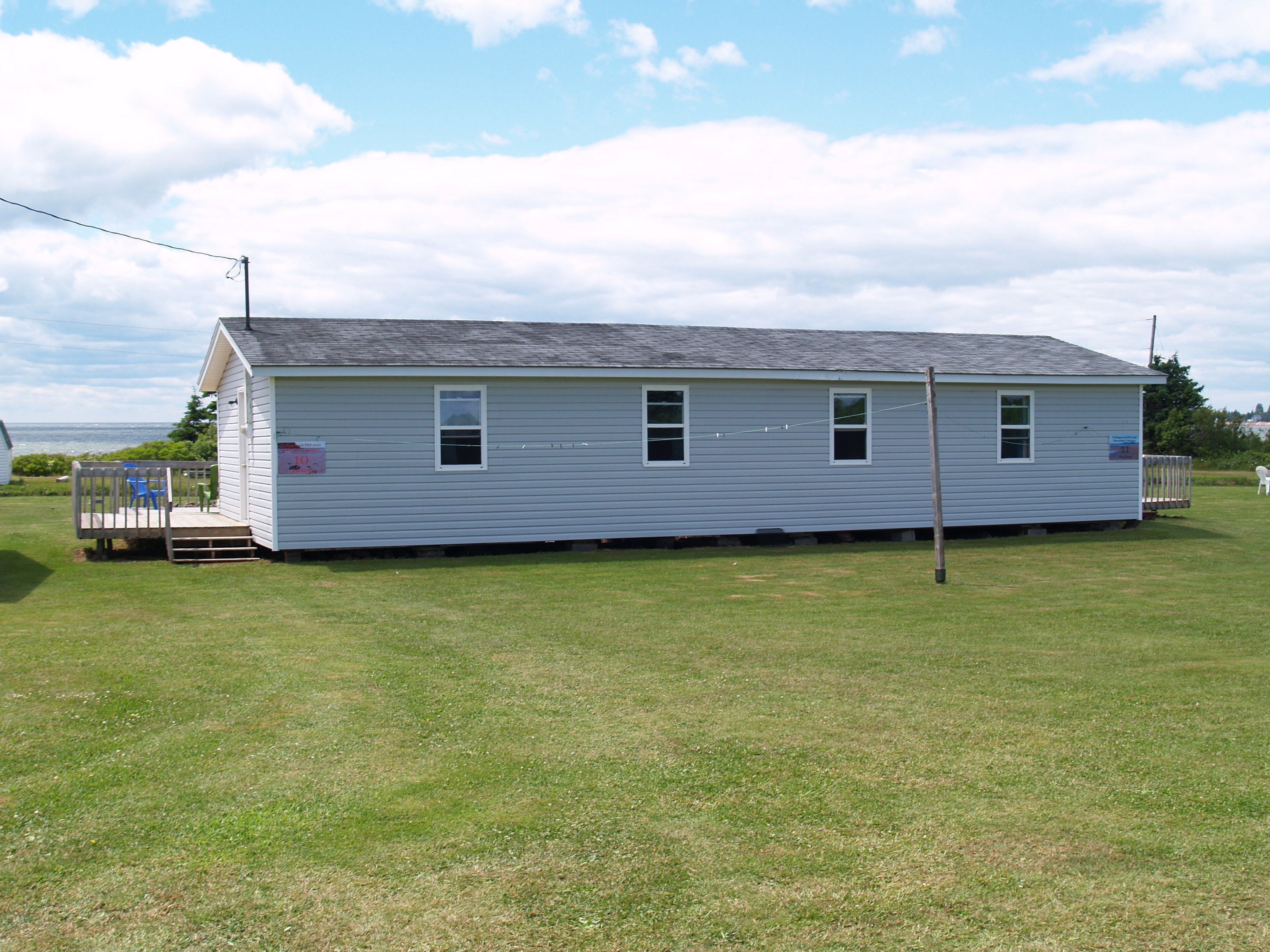 A single-story, white wooden house with a small porch and a fenced yard.