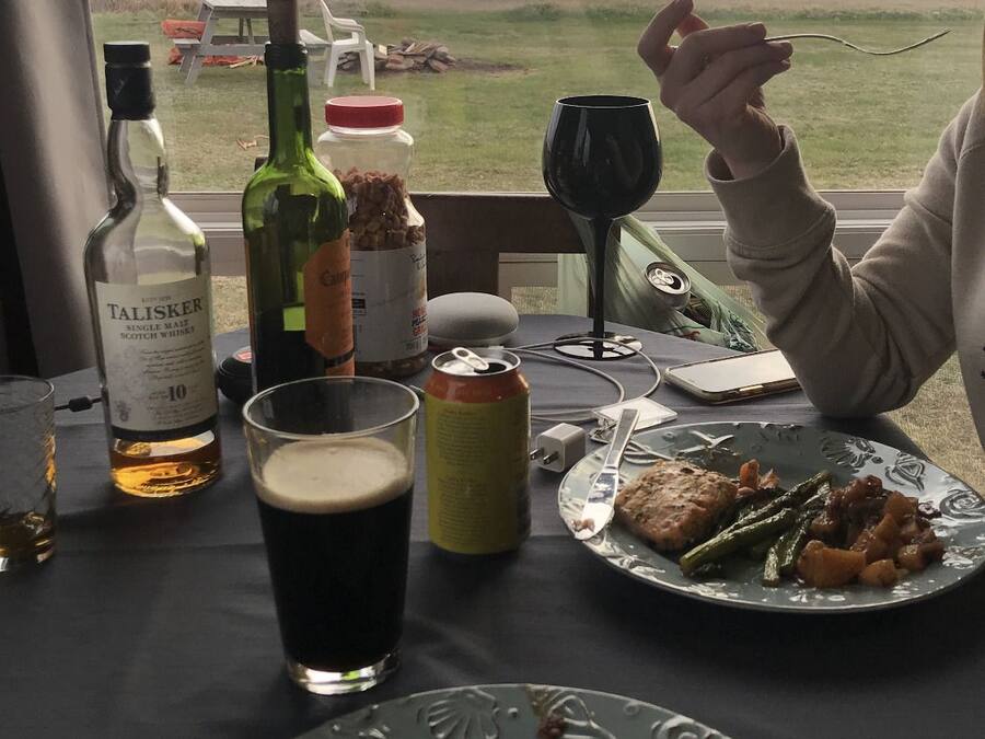 Une table avec des assiettes de nourriture, un verre de bière et des bouteilles d’alcool.