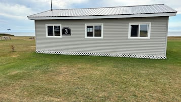 A small, single-story building with a metal roof and white siding, labeled with the number 3 and a sign that reads "Cottages on the Bay."