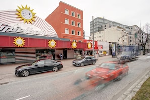 A building with a red facade and multiple windows, a sign for 'Kiosk' and 'Hotel', and a large sun emblem. - Hotel North (Hamburg)