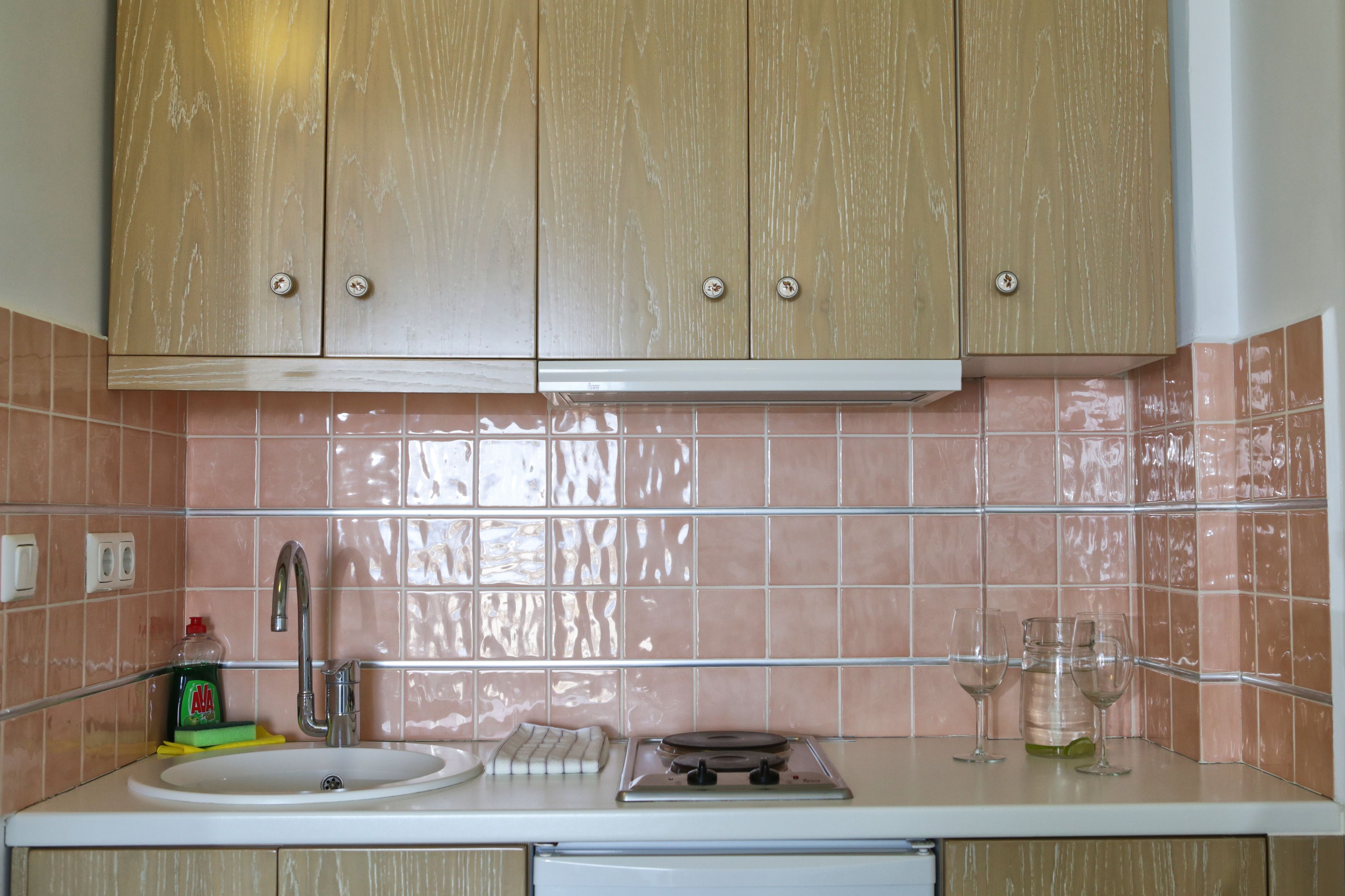 A kitchen with wooden cabinets, a sink, a stove, and a tiled backsplash.