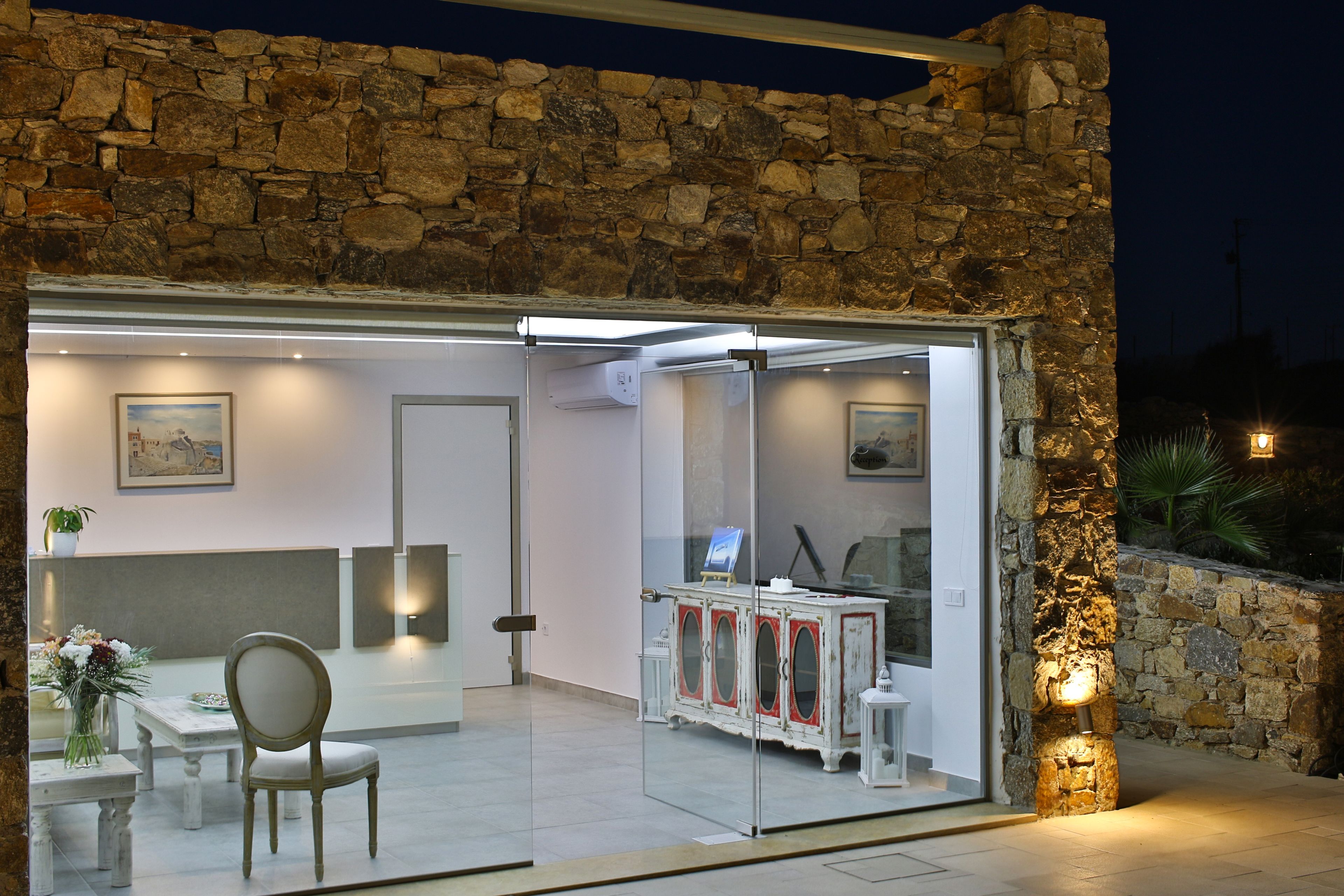 Un interior moderno con una pared de piedra, una puerta de cristal que da a un comedor y un armario blanco con detalles rojos.