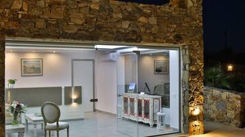 Un interior moderno con una pared de piedra, una puerta de cristal que da a un comedor y un armario blanco con detalles rojos.