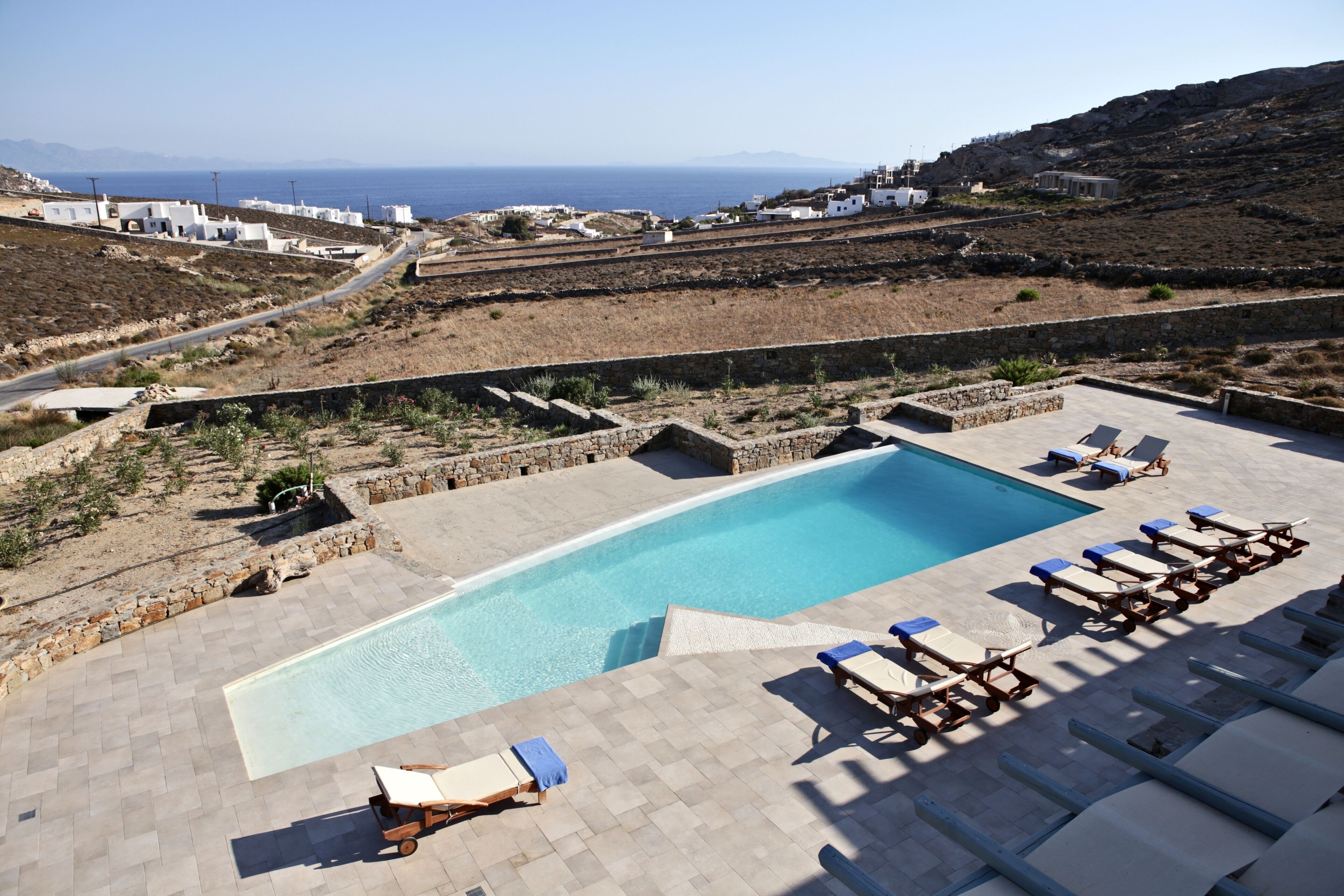 Zona de piscina con sillas de descanso y vistas al mar.