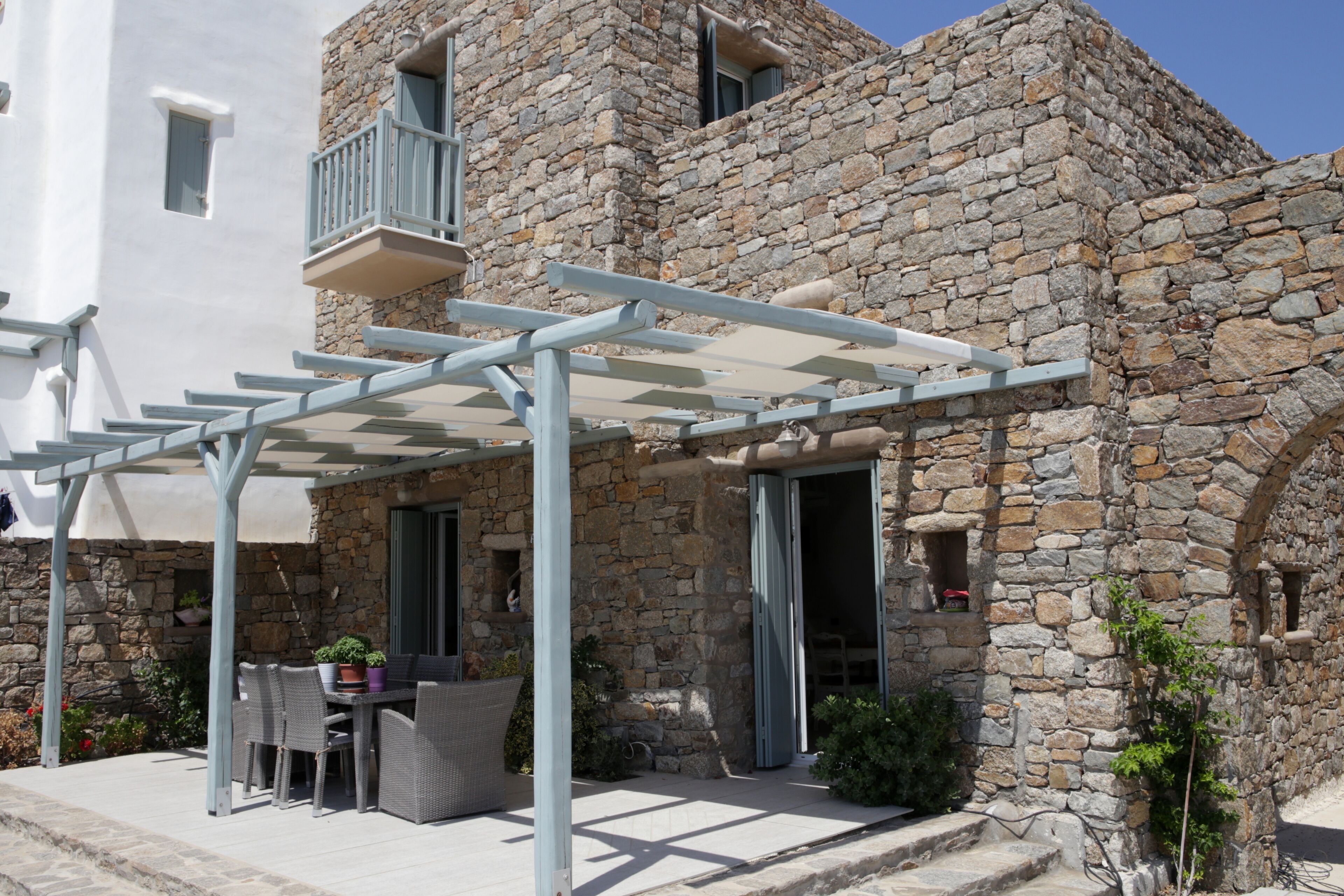 A stone building with a covered patio area featuring outdoor furniture and a pergola.