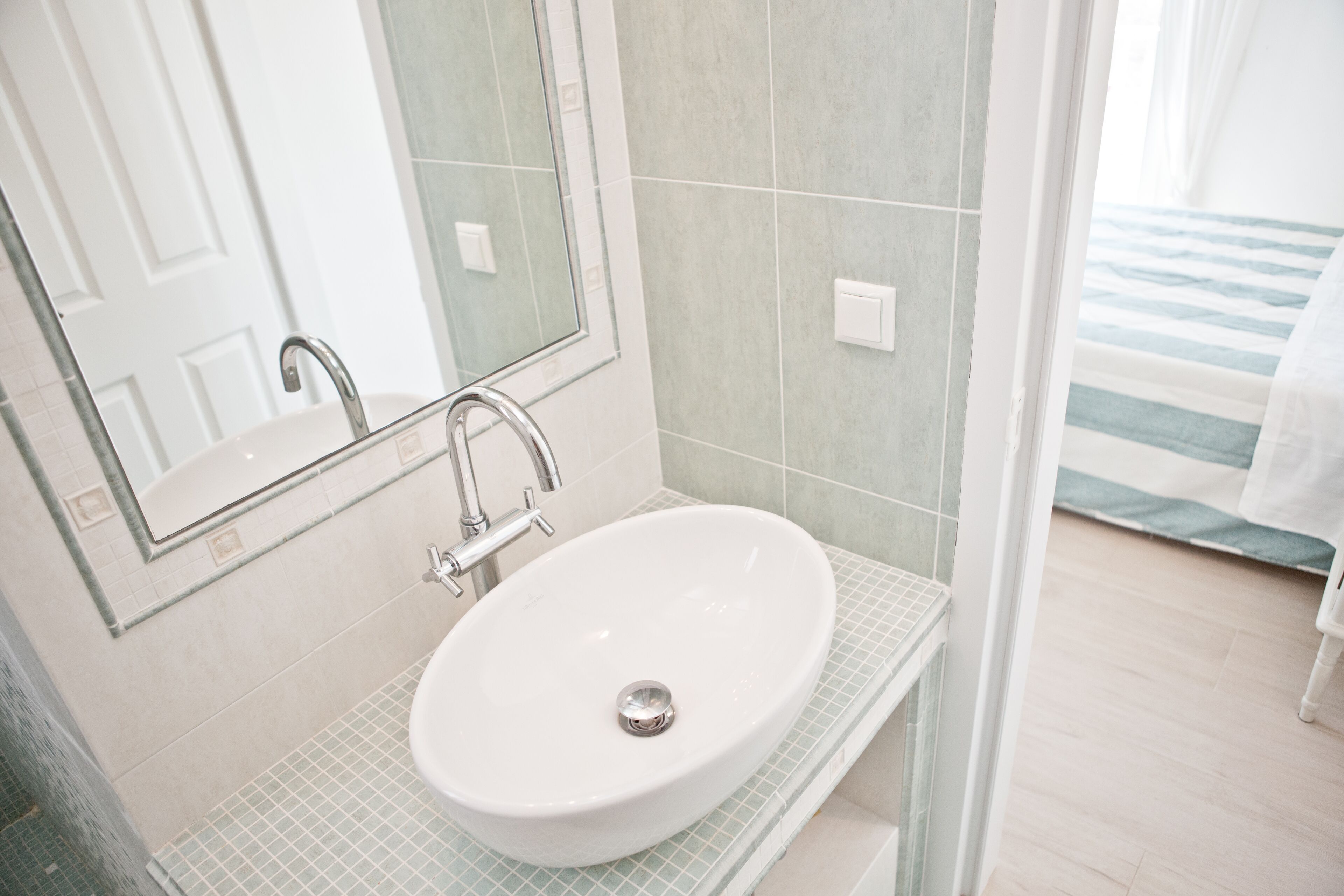 A bathroom with a white sink, a mirror, and a shower area.