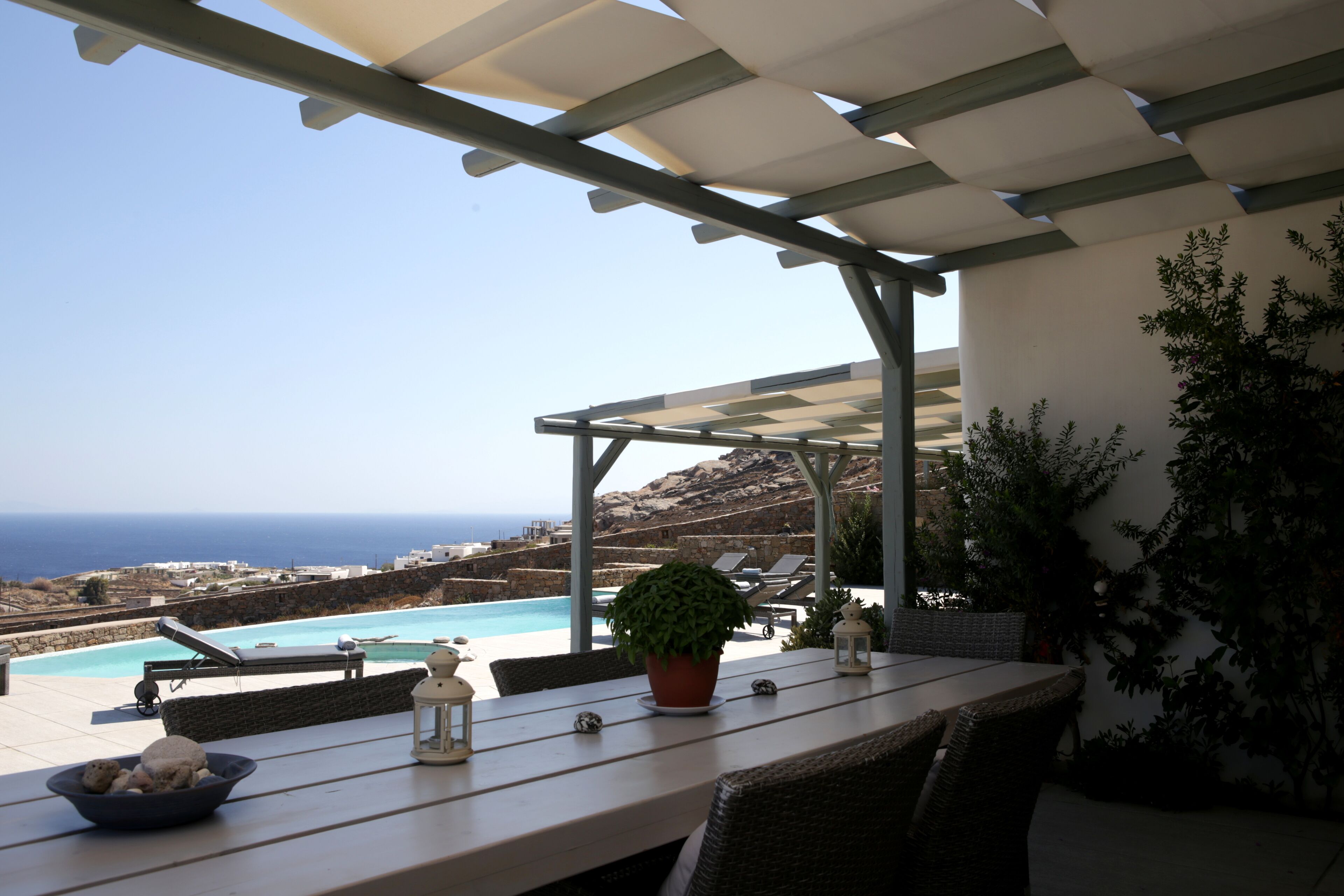 A terrace with a view of the sea, a pool, and outdoor seating.