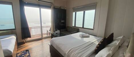 A hotel room with a bed, a small table, a chair, a window, and an air conditioning unit.