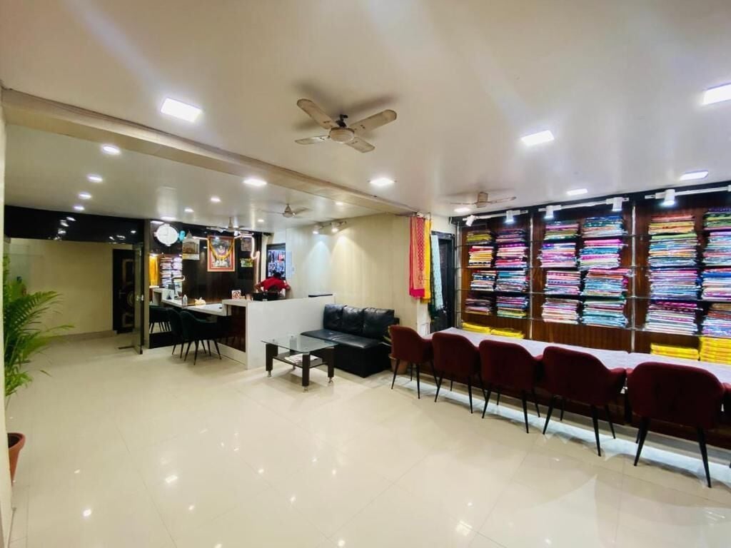 A spacious room with a dining area, a sofa, and a wall displaying folded fabrics.