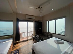 Habitación de hotel con cama, sofá, balcón y vista al mar, además de aire acondicionado.