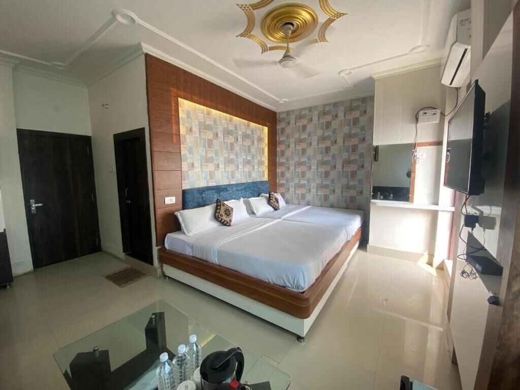 A hotel room with a large bed, a glass table, a ceiling fan, and a television.