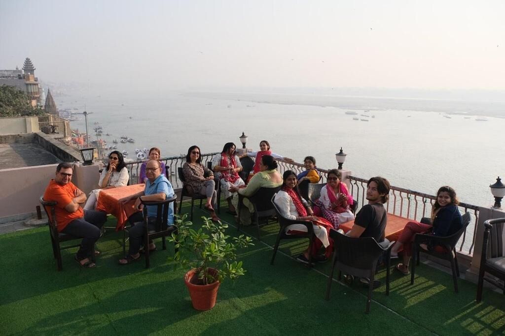 A group of people seated at tables on a terrace with a view of the sea.
