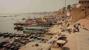 A riverside area with boats docked, a bridge, and buildings along the riverbank. - Hotel Sita (Varanasi)