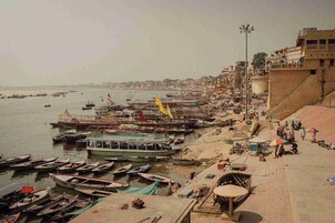 A riverside area with boats docked, a bridge, and buildings along the riverbank.