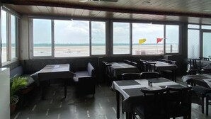 Un ristorante con ampie finestre, tavoli e una ventola a soffitto.