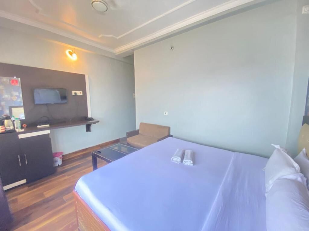 Une chambre d’hôtel avec un lit, un téléviseur fixé au mur, une petite table et une chaise.