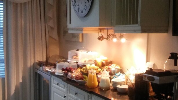 A kitchen with white cabinets, a clock, and a breakfast buffet. - Altona Guest House (Cape Town)