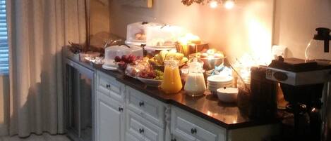 Una cocina con armarios blancos, un reloj y un bufé de desayuno.
