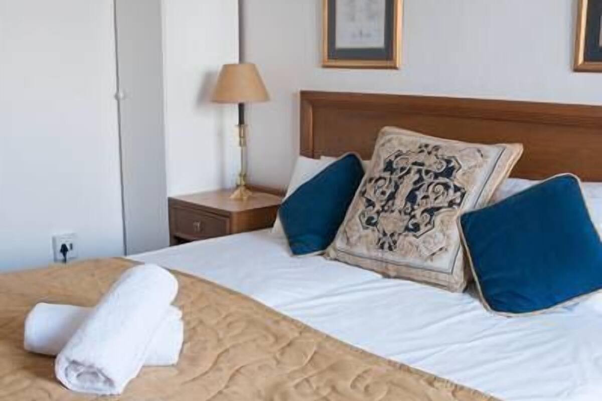 A hotel room with a bed, a nightstand, a lamp, and a wardrobe.