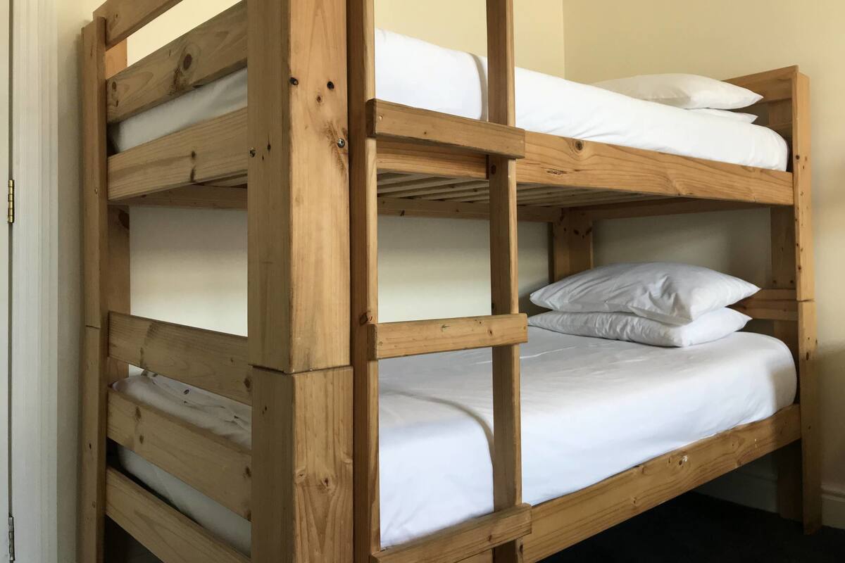 A wooden bunk bed with white bedding.
